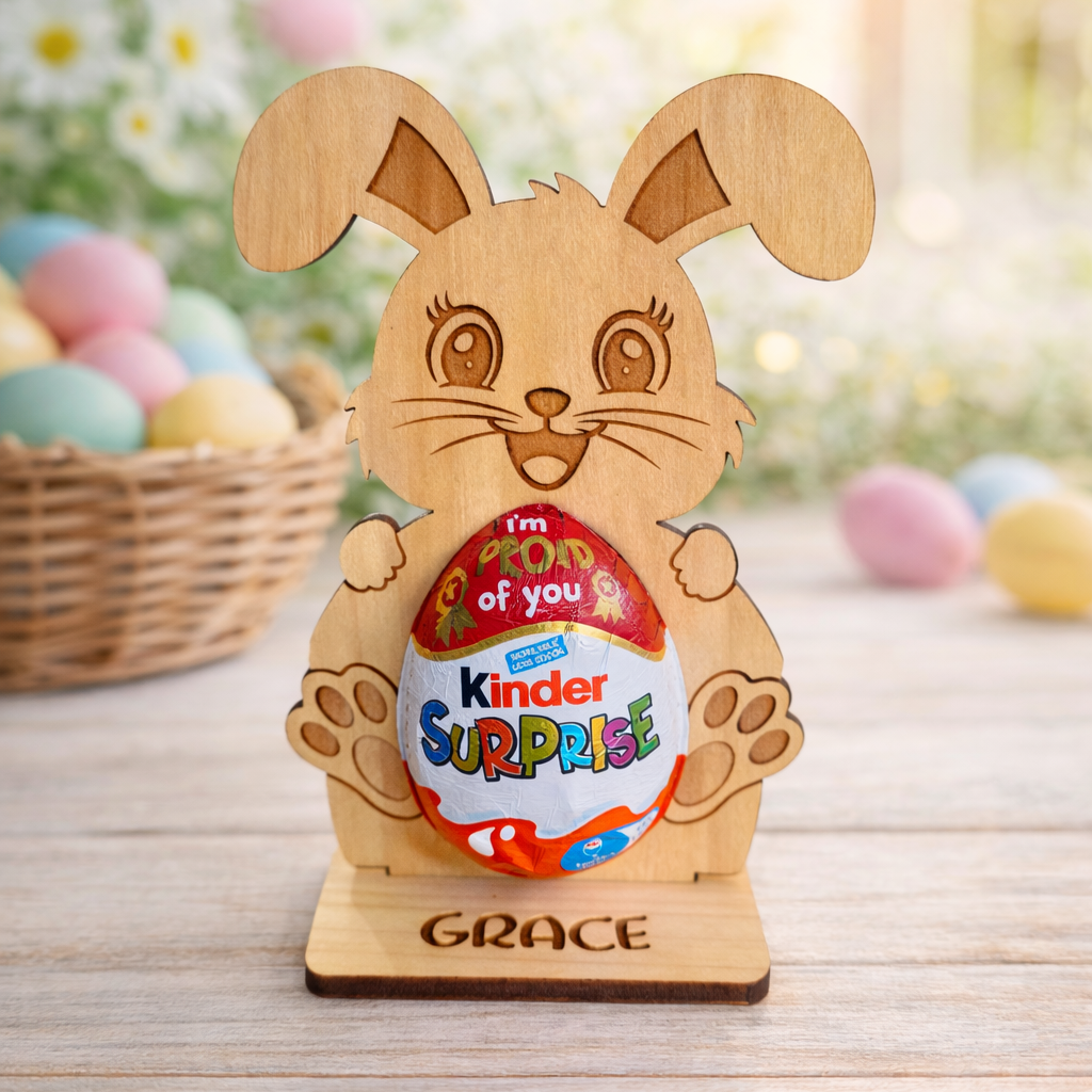 Wooden rabbit-shaped holder with a Kinder Surprise egg on a wooden surface with Easter eggs and basket in the background.