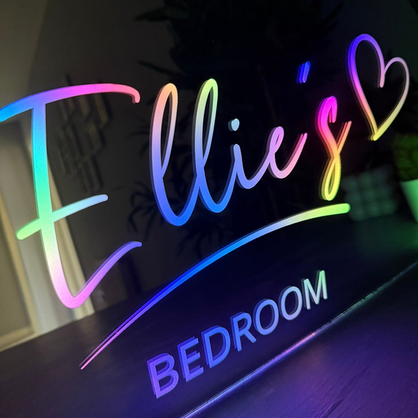 Neon sign with 'Ellie's Bedroom' in colorful letters on a dark background
