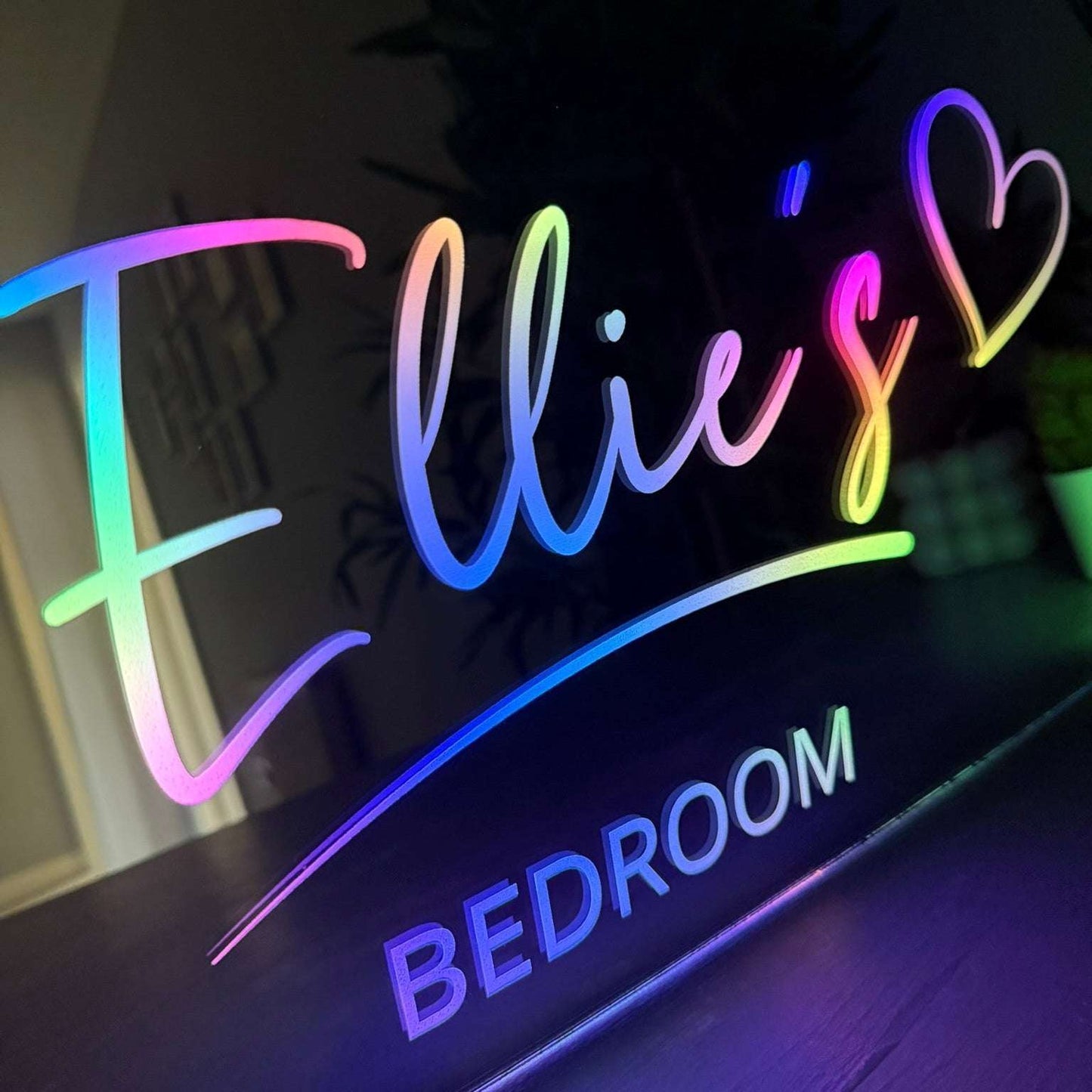 Neon sign with 'Ellie's Bedroom' in colorful letters on a dark background