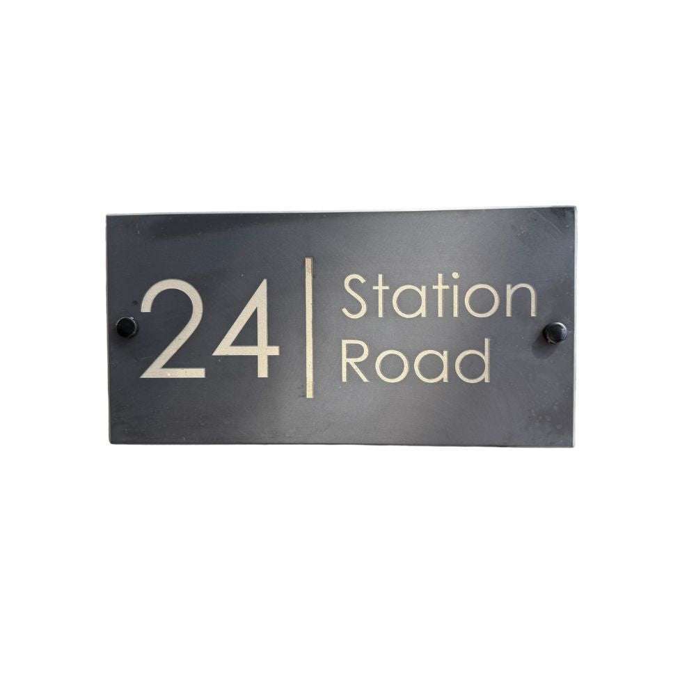 Rectangular black house number sign with '24 Station Road' text on a white background