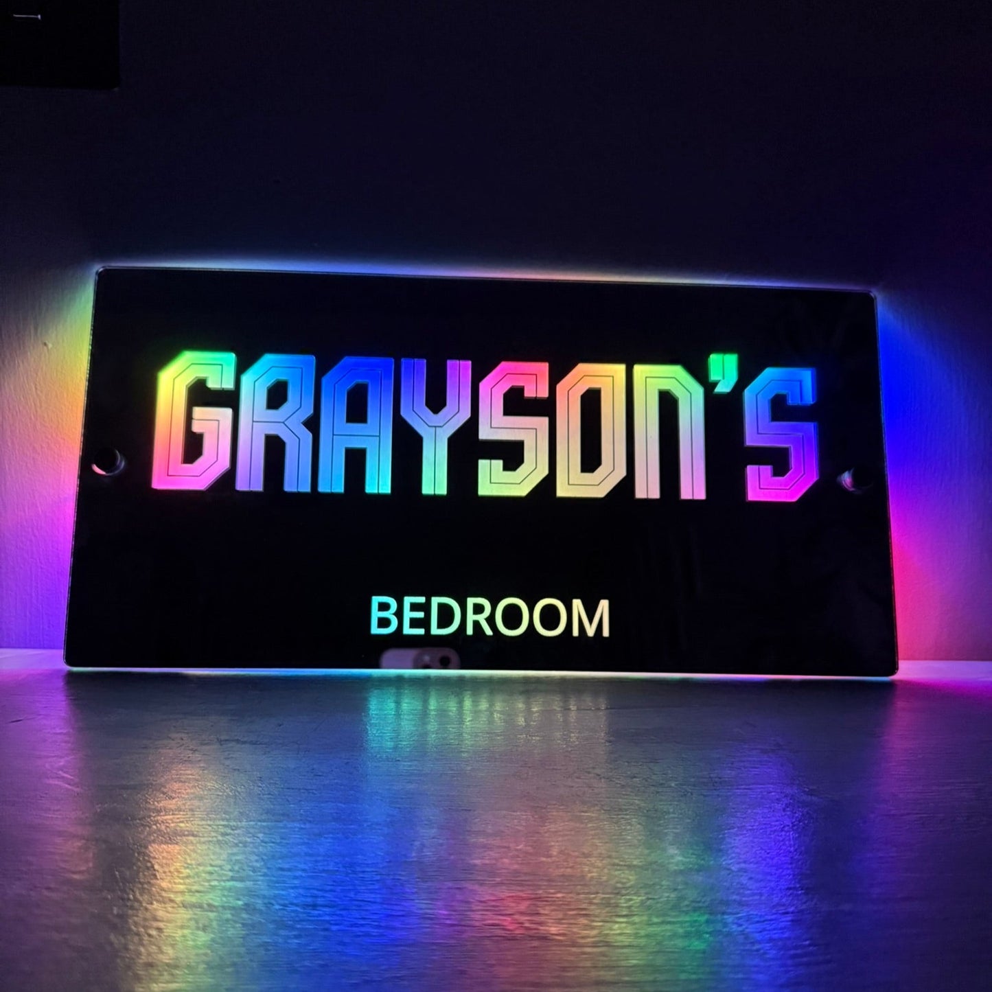 Custom LED name sign mounted on a child’s bedroom wall, glowing in vibrant colours