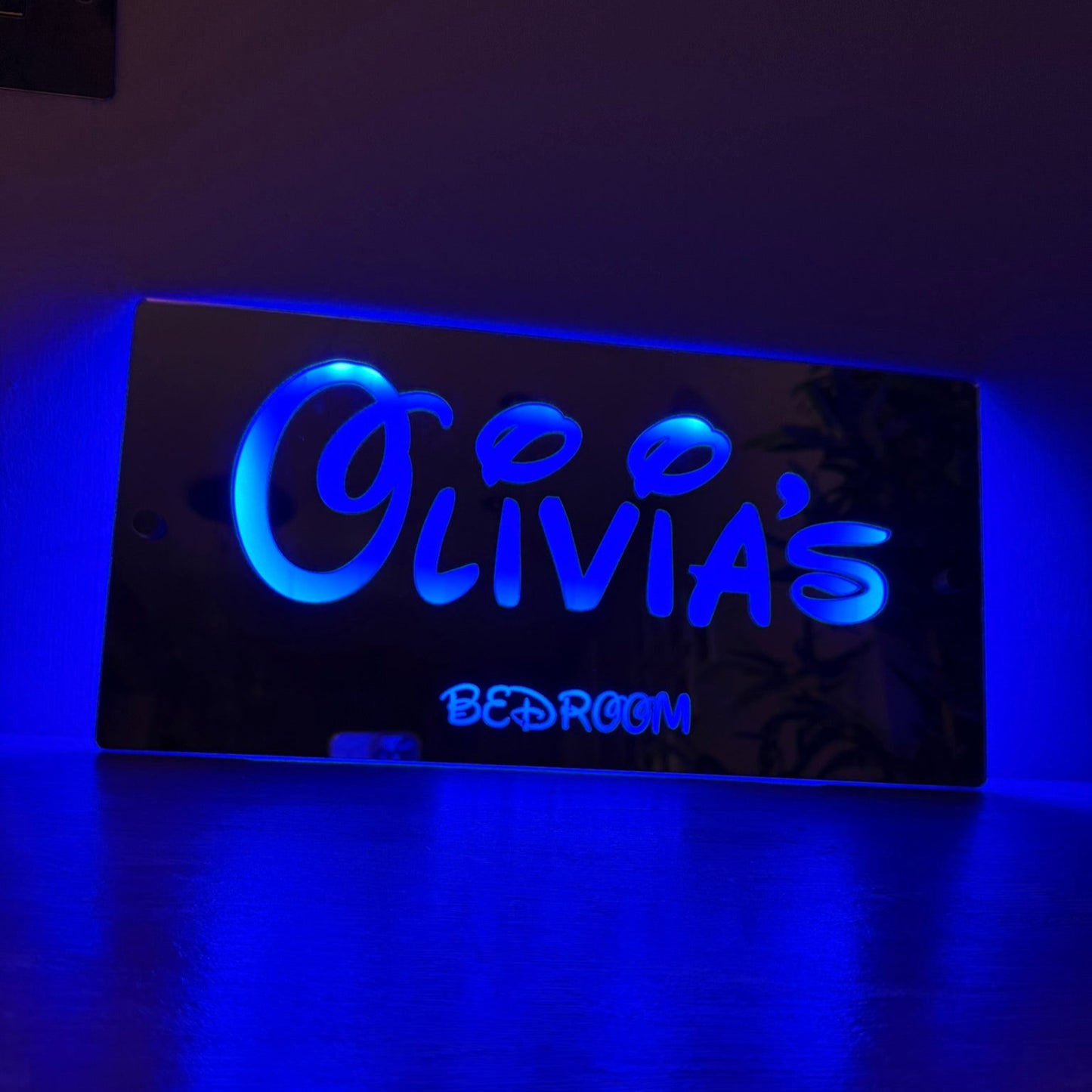 Custom LED mirror sign mounted on a child’s bedroom wall glowing in vibrant colour settings.