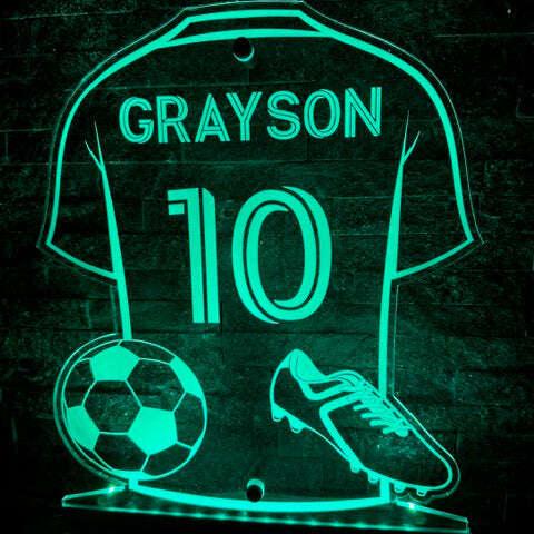 Personalised LED football sign glowing in a fan’s bedroom with rugby-themed night light nearby