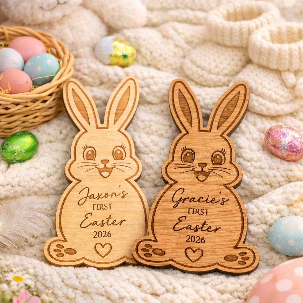 Wooden bunny-shaped ornaments for 'Jason's First Easter 2026' and 'Gracie's First Easter 2026' on a soft fabric background with Easter eggs and flowers.