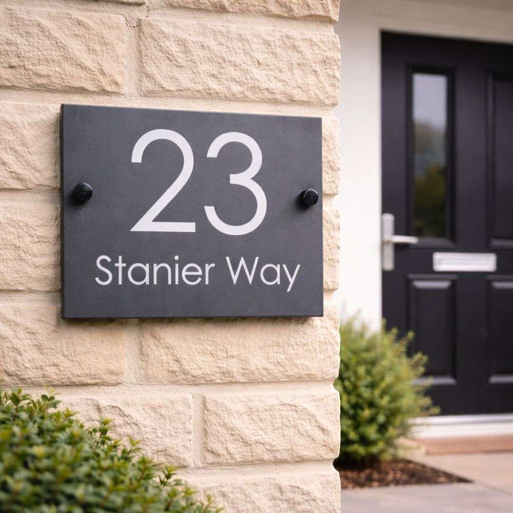 House number sign '23 Stanier Way' on a stone wall with a black door.