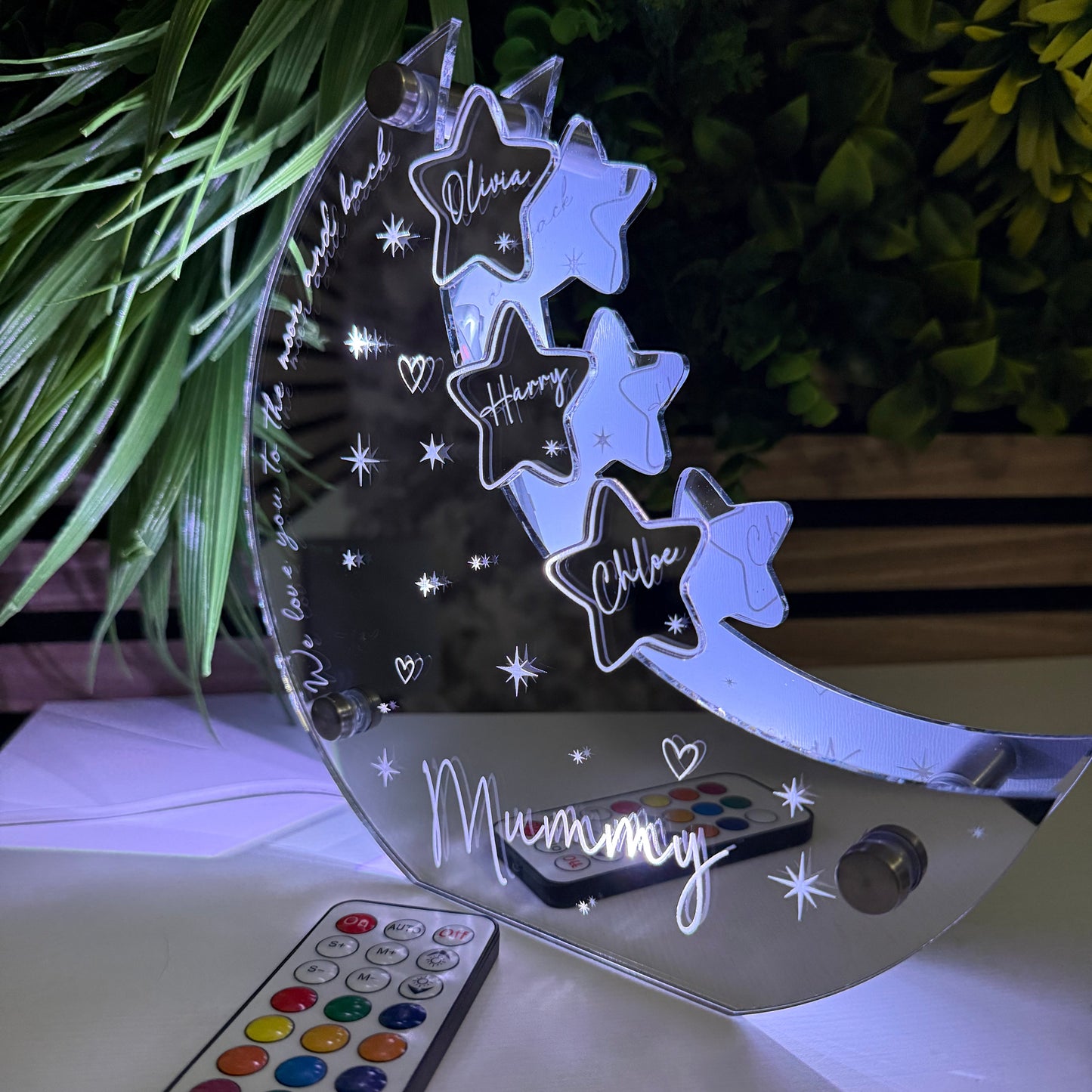 Decorative night light with star designs and a remote control on a white surface.