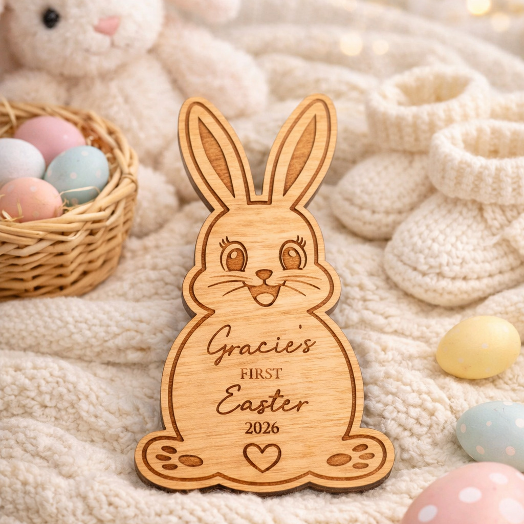 Wooden bunny ornament with 'Gracies First Easter 2026' engraving on a soft fabric background with Easter eggs and a plush toy.