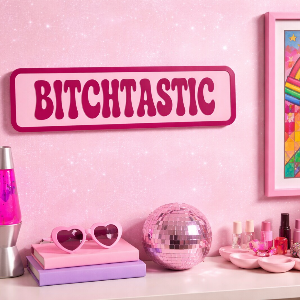 Decorative shelf with pink and silver lava lamp, heart-shaped sunglasses, disco ball, and framed artwork on a pink wall.