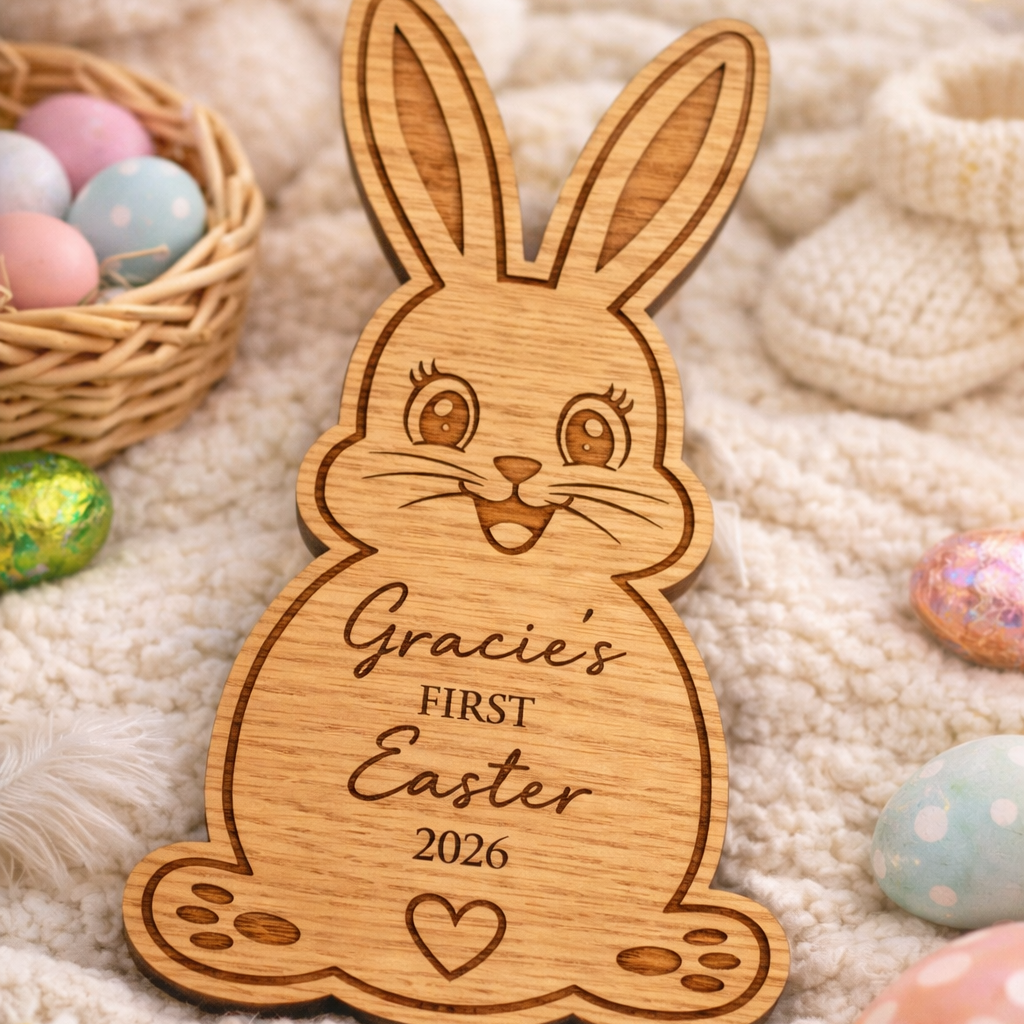 Wooden Easter bunny ornament with 'Gracie's First Easter 2026' engraving on a soft fabric background with Easter eggs.