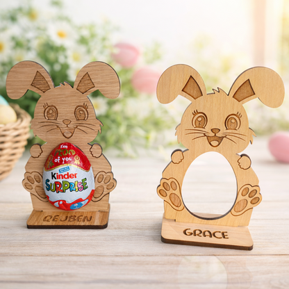Two wooden rabbit-shaped holders with personalized names on a blurred Easter background.