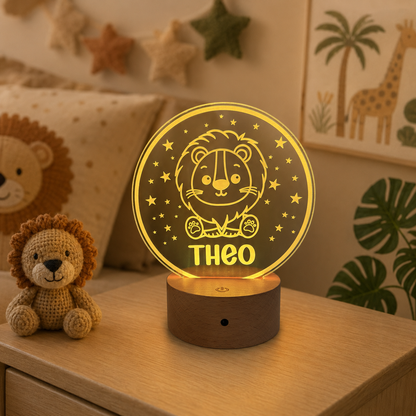 A personalized 3D optical illusion night light shaped like a round moon with a lion illustration and the name 'THEO' in yellow, sitting on a wooden base on a wooden table in a child's bedroom setting.