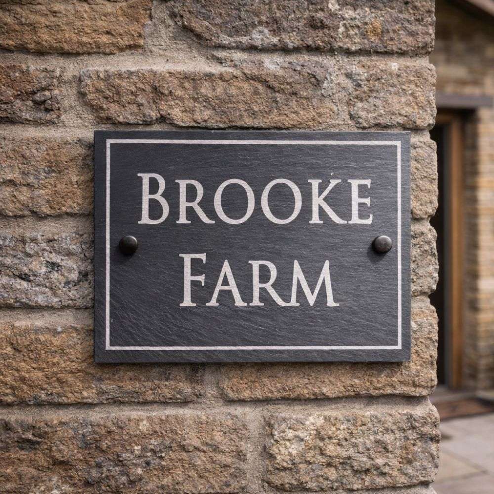 Slate house sign with 'Brooke Farm' on a stone wall