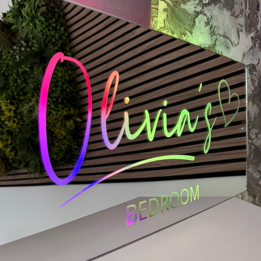 Decorative sign with 'Olivia's Bedroom' in colorful letters against a striped background.
