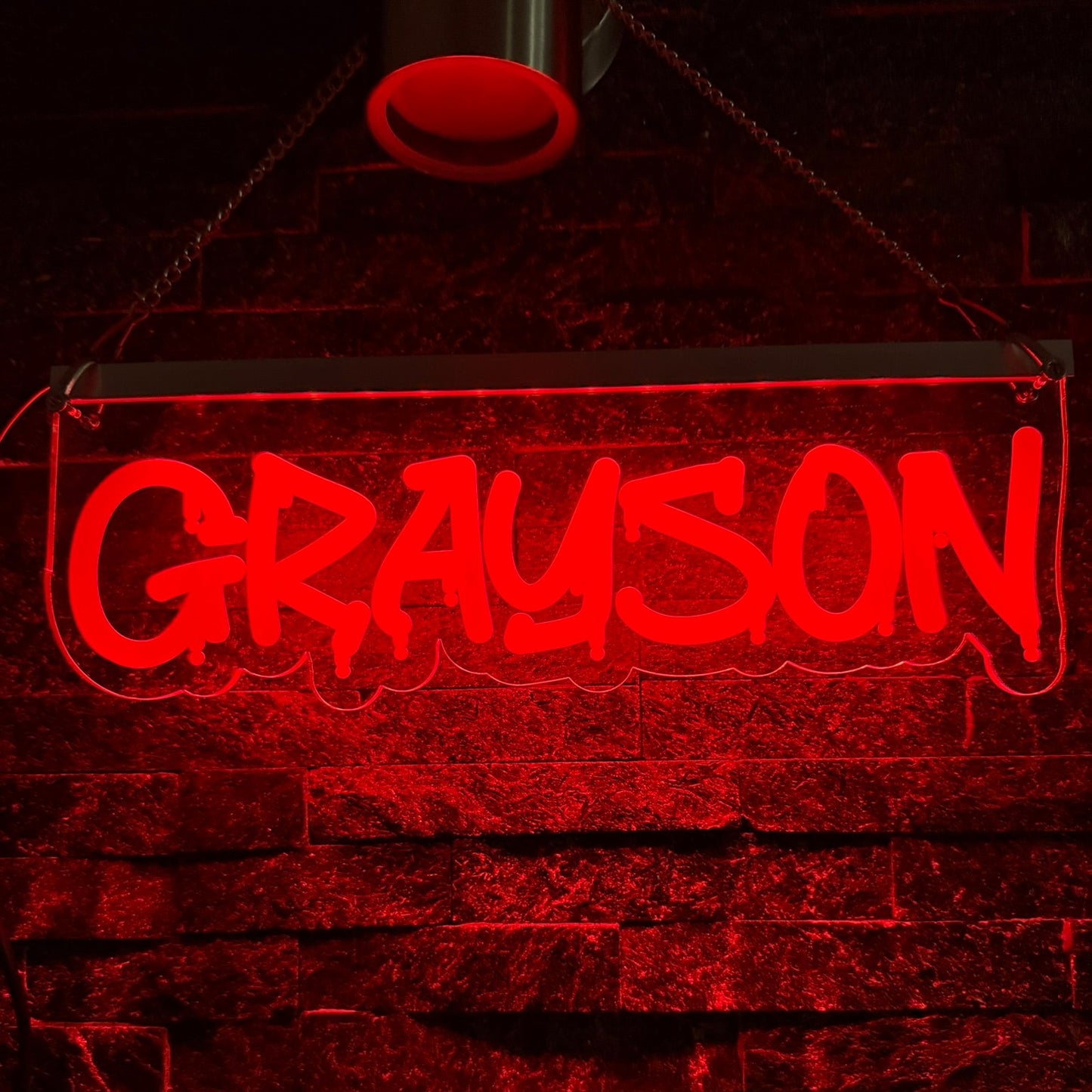 Neon sign with the name 'Grayson' on a brick wall background
