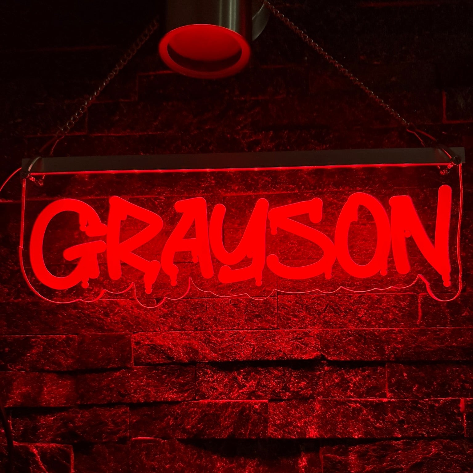 Neon sign with the name 'Grayson' on a brick wall background