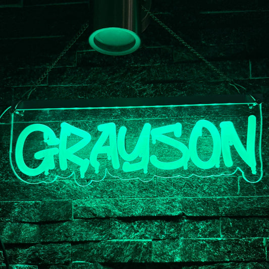 Neon sign with the word 'GRAYSON' on a stone wall background