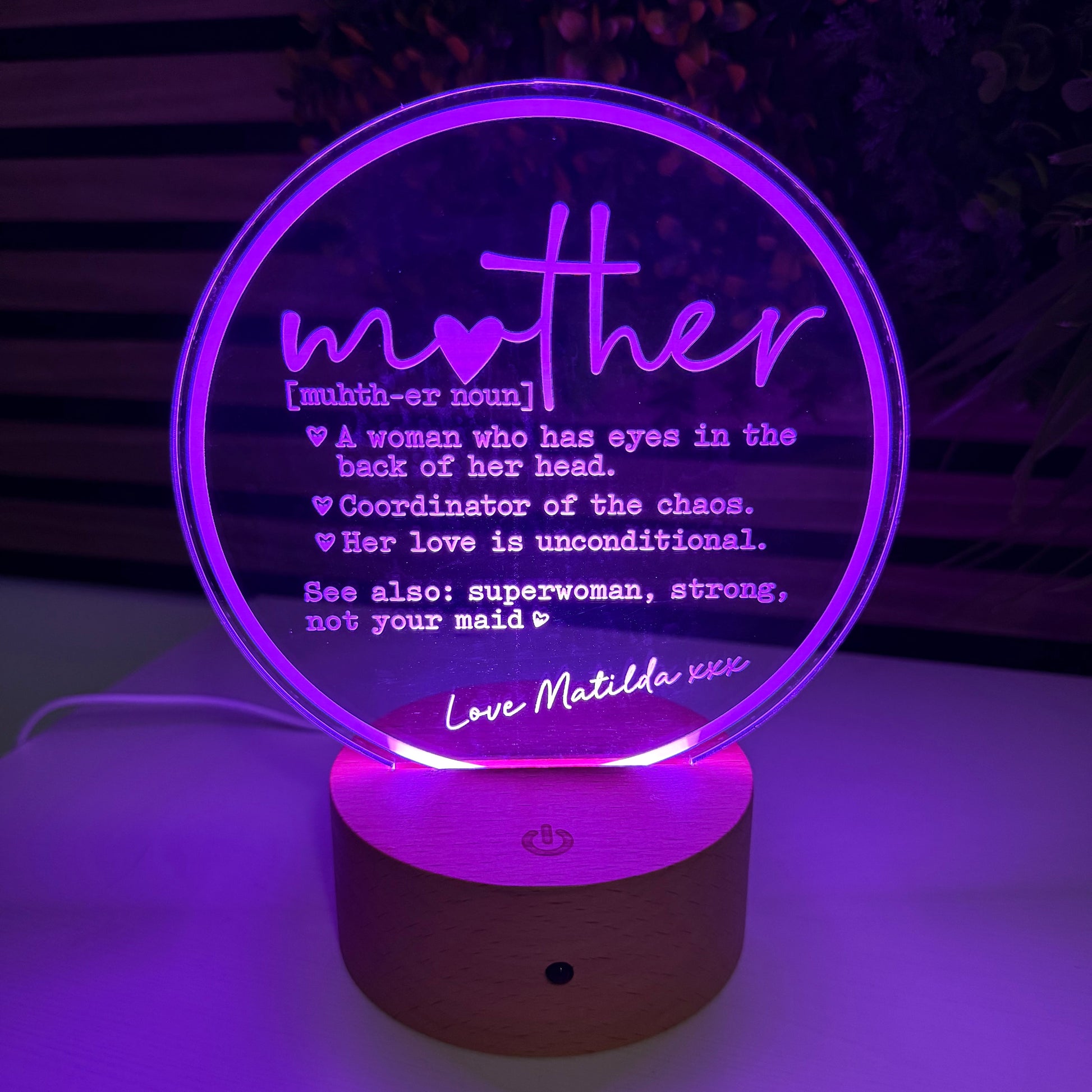 Decorative lamp with 'mother' text and purple glow on a dark background