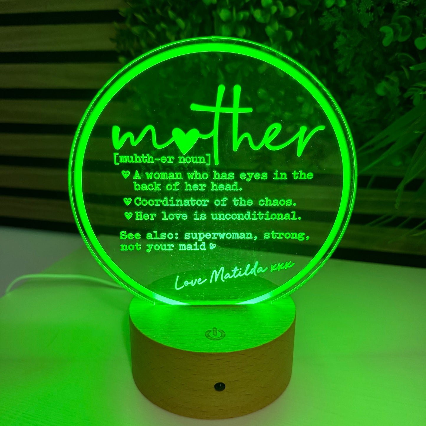 Decorative night light with green glow on a wall, featuring text.