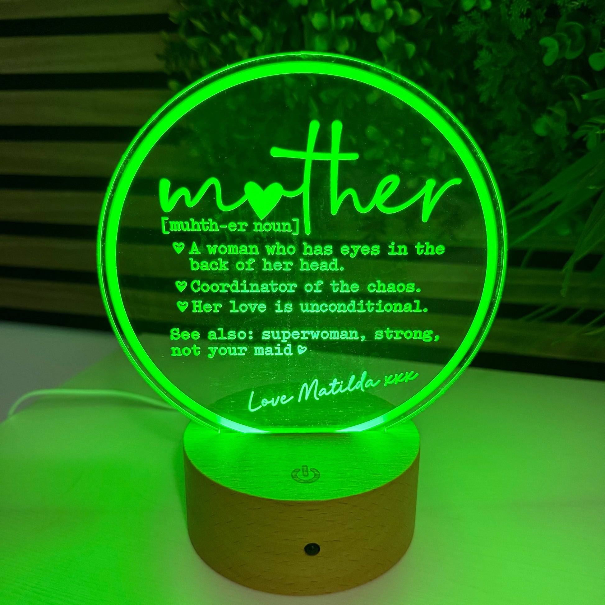 Decorative night light with green glow on a wall, featuring text.
