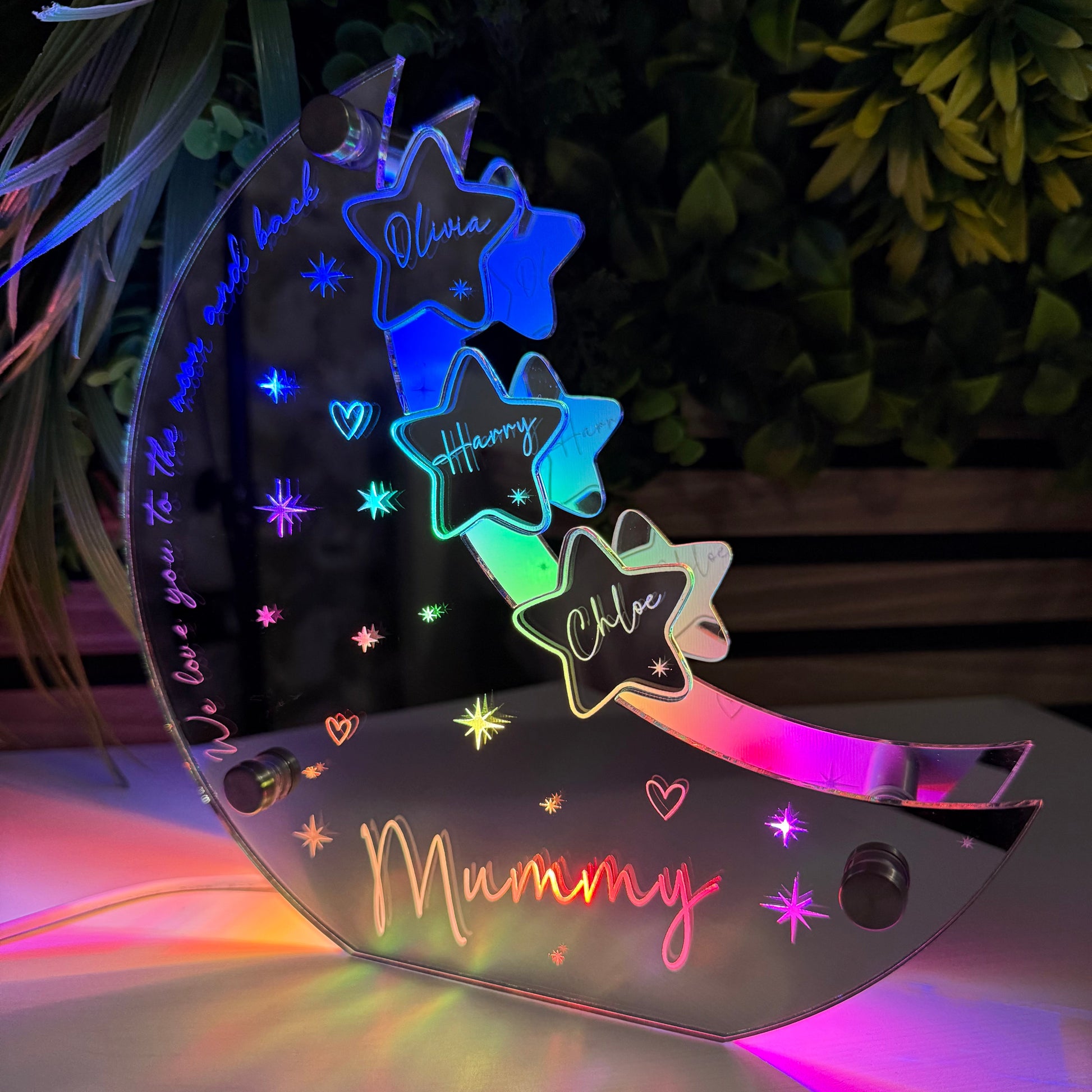 Colorful fairy wings with 'Mummy' and star designs, illuminated against a dark background.