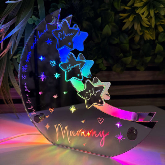 Colorful fairy wings with 'Mummy' and star designs, illuminated against a dark background.
