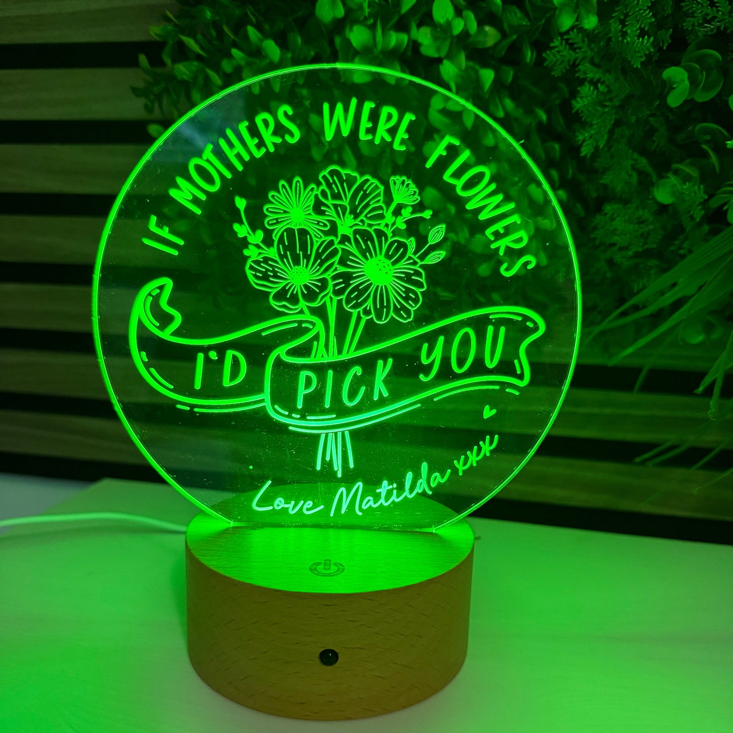 Green LED night light with floral design and text on a white wall.