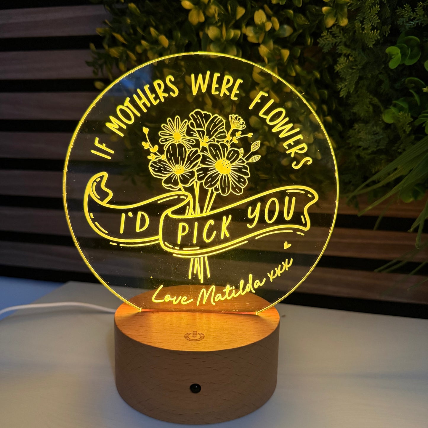 Decorative wall light with floral design and text on a plant and wall background