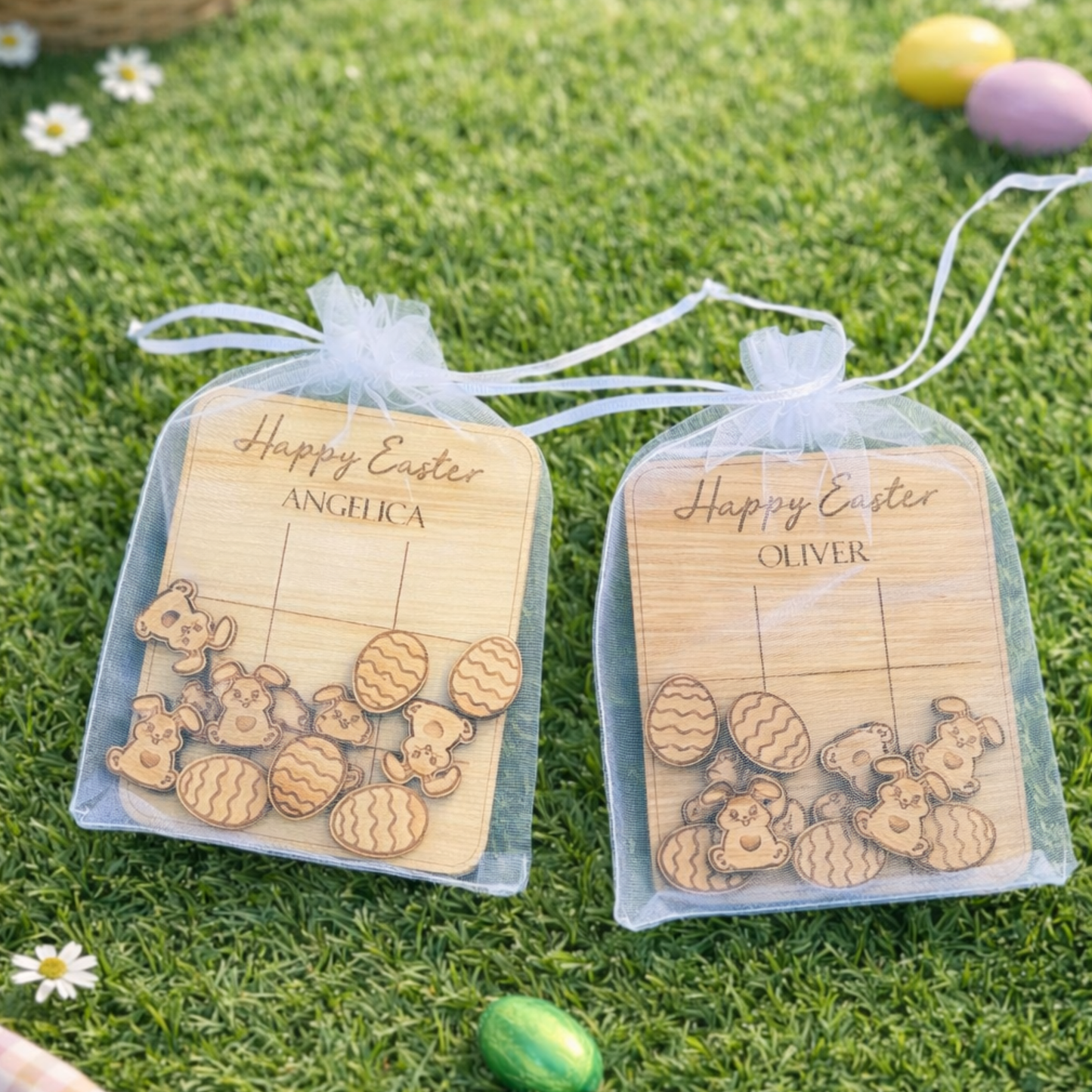 Two clear bags with wooden Easter-themed items and personalized names on a grassy background.