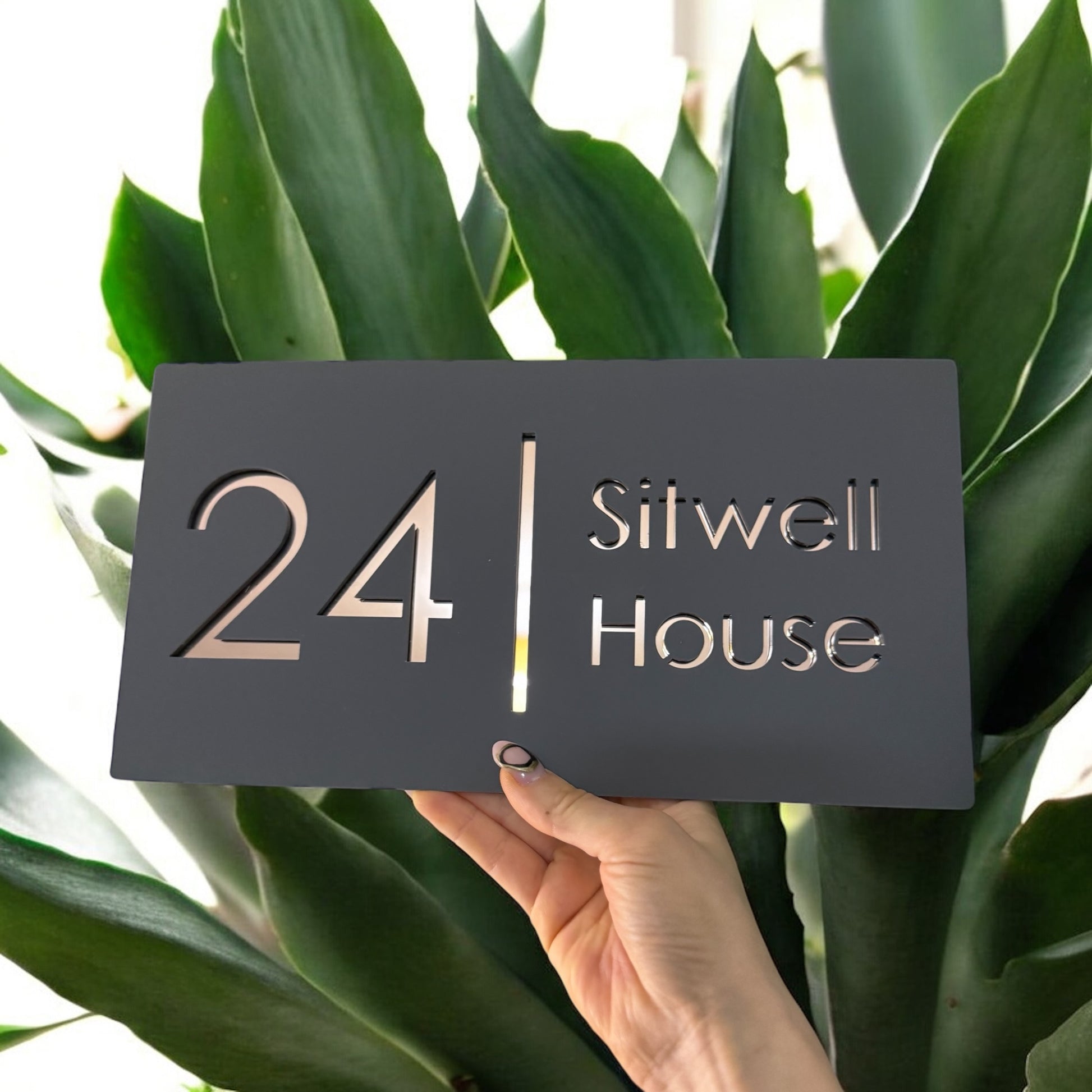 Rose gold acrylic house number sign mounted on brick exterior wall