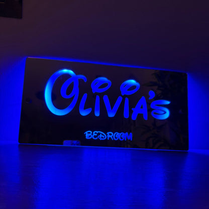 Custom LED mirror sign mounted on a child’s bedroom wall glowing in vibrant colour settings.